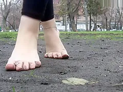 Girl shows her dirty feet on a park bench